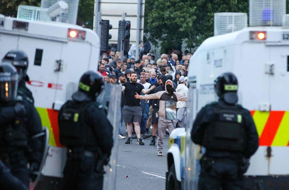 Riot Police stand guard buy armoured Police Land Rovers as protestors gather during a thrid night of anti-immigration demonstrations in Ballymena, Northern Ireland yesterday. — AFP pic