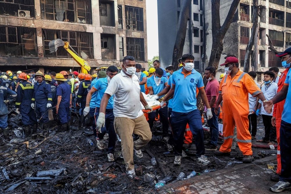 Lone survivor emerges from fiery Air India crash in Ahmedabad that killed 260, UK national identified Rescue officials carry a victim's body at the site where Air India flight 171 crashed in a residential area near the airport in Ahmedabad yesterday. — AFP pic