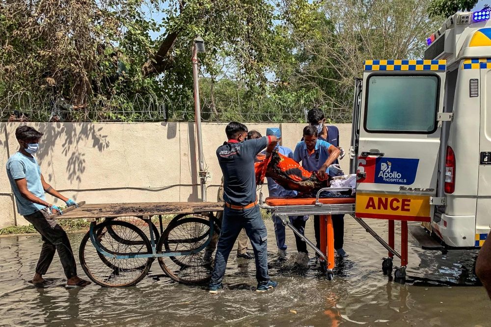Medics transfer bodies of victims onto an ambulance after Air India Flight 171 crashed in a residential area near the airport in Ahmedabad yesterday. — AFP pic