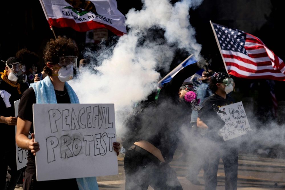 A demonstrator throws a tear gas canister back at law enforcement during clashes that erupted after authorities declared an unlawful assembly during the ‘No Kings’ protest against the Trump administration in Los Angeles on June 14, 2025 on the day of Trump’s military parade in Washington, DC. Tens of thousands of protesters rallied nationwide yesterday against Donald Trump ahead of a huge military parade on the US president’s 79th birthday — as the killing of a Democratic lawmaker underscored the deep divisions in American politics. — AFP pic