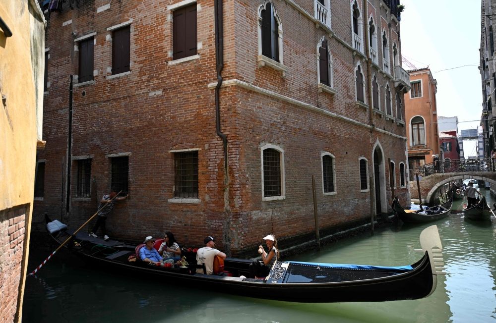 Tourists enjoy a gondola ride in a canal of the historic city center in Venice, on June 22, 2025. — AFP pic