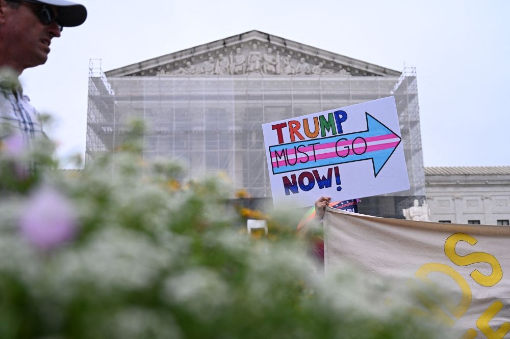 A demonstrator holds up an anti-Trump sign outside the US Supreme Court in Washington, DC, on June 27, 2025. The Supreme Court is to issue its final rulings on Friday ahead of its summer break, including cases involving birthright citizenship, porn site age verification, students and LGBTQ-themed content, and voting rights. — AFP pic