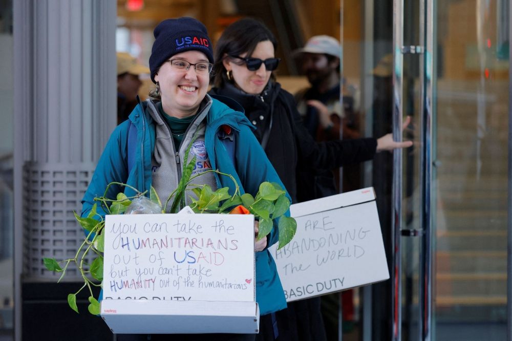 Recently fired US Agency for International Development (USAID) staff carry boxes with a message as they leave work and are applauded by former USAID staffers and supporters during a sendoff outside USAID offices in Washington, D.C. February 21, 2025. — Reuters pic