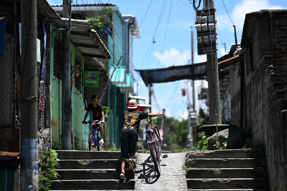 Two boys play on their bicycles in a street of the 10 de Octubre residential neighbourhood in San Marcos, El Salvador, on June 14, 2025. — AFP pic