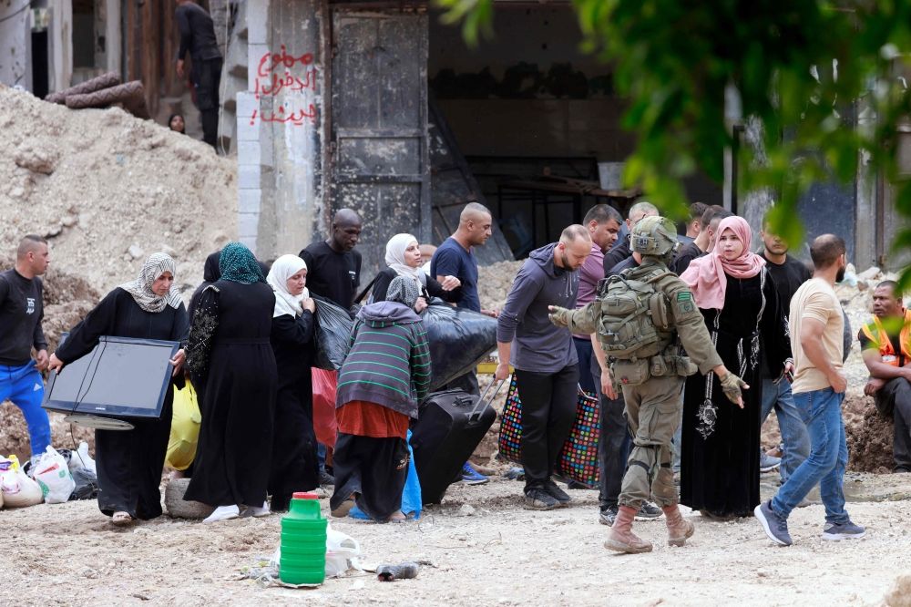 An Israeli soldier gestures as Palestinians carry their belongings after being ordered to leave their homes during an Israeli operation in the Tulkarem camp for refugees in the north-west of the occupied West Bank on May 2, 2025. — AFP pic