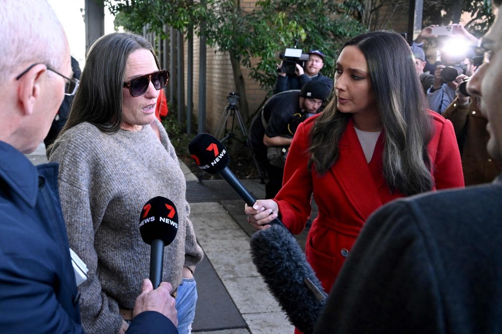 Members of the media talk to a friend of Erin Patterson as she leaves the Latrobe Valley Magistrates' Court in Morwell, where Patterson was found by a jury today. — AFP pic