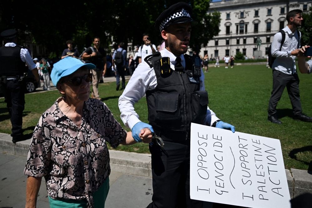 Pro-Gaza activists detained across five cities as UK enforces terror ban on protest group Palestine Action A Police officer holds a placard belonging to an arrested Protester as people gather in support of the pro-palestinian group 'Palestine Action', in Parliament Square, London on July 12, 2025. — AFP pic