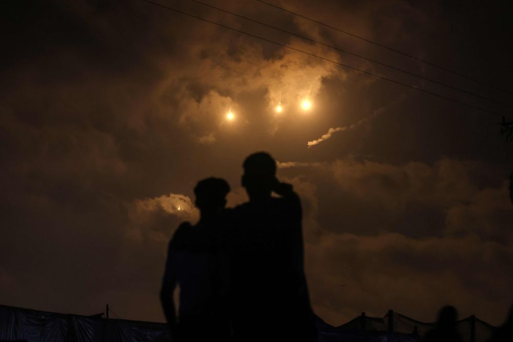 Displaced Palestinians watch from the al-Mawasi refugee camp as flares launched by Israeli forces light up the sky above nearby Khan Yunis in the southern Gaza Strip on July 21, 2025. — AFP pic Displaced Palestinians watch from the al-Mawasi refugee camp as flares launched by Israeli forces light up the sky above nearby Khan Yunis in the southern Gaza Strip on July 21, 2025. — AFP pic