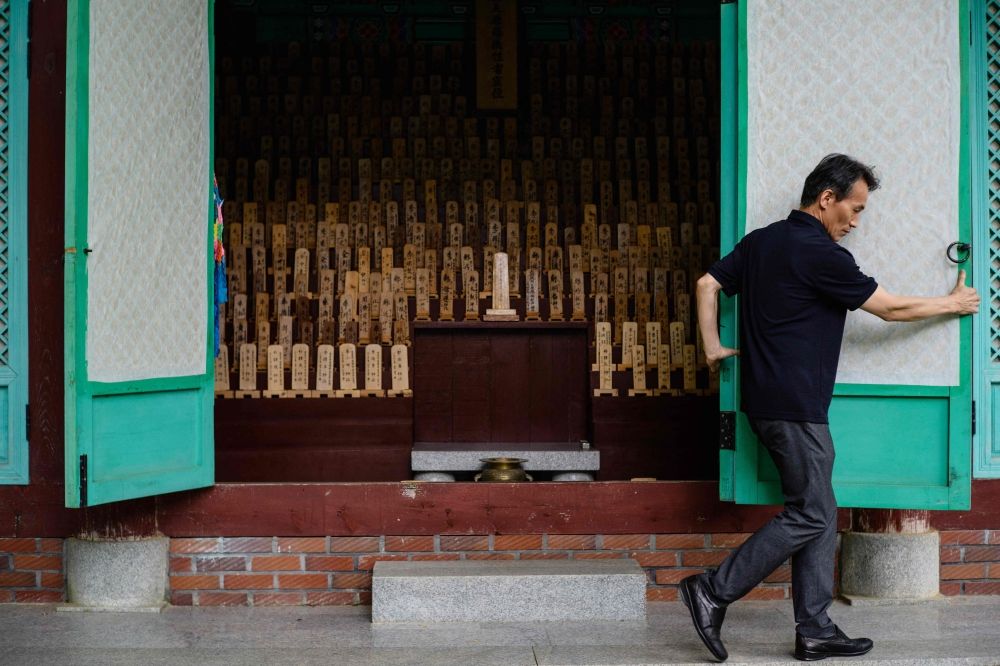 This photo shows Korean Red Cross secretary-general Kang Soohan opening the doors to a traditional structure holding wooden plaques bearing the names of deceased victims behind the Hapcheon Atomic Bomb Victim Welfare Center. — AFP pic This photo shows Korean Red Cross secretary-general Kang Soohan opening the doors to a traditional structure holding wooden plaques bearing the names of deceased victims behind the Hapcheon Atomic Bomb Victim Welfare Center. — AFP pic