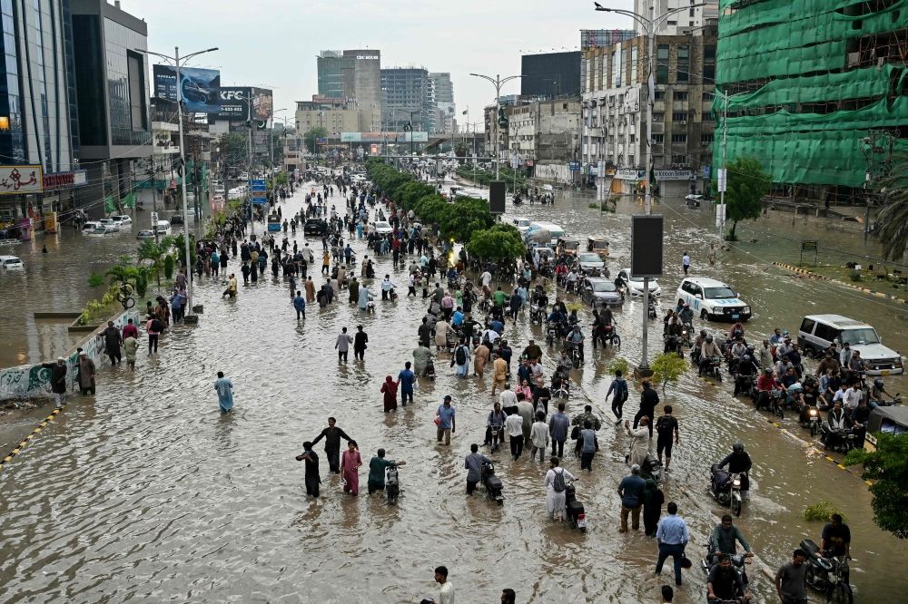 People wade through a flooded street after heavy rainfall in Karachi on August 19, 2025. — AFP pic People wade through a flooded street after heavy rainfall in Karachi on August 19, 2025. — AFP pic