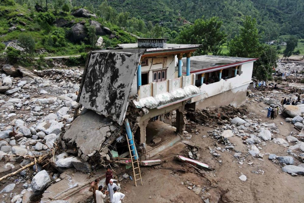 An aerial view shows flood survivors standing near a damaged house surrounded by heavy rocks in the Buner district of mountainous Khyber Pakhtunkhwa province on August 17, 2025. — AFP pic An aerial view shows flood survivors standing near a damaged house surrounded by heavy rocks in the Buner district of mountainous Khyber Pakhtunkhwa province on August 17, 2025. — AFP pic
