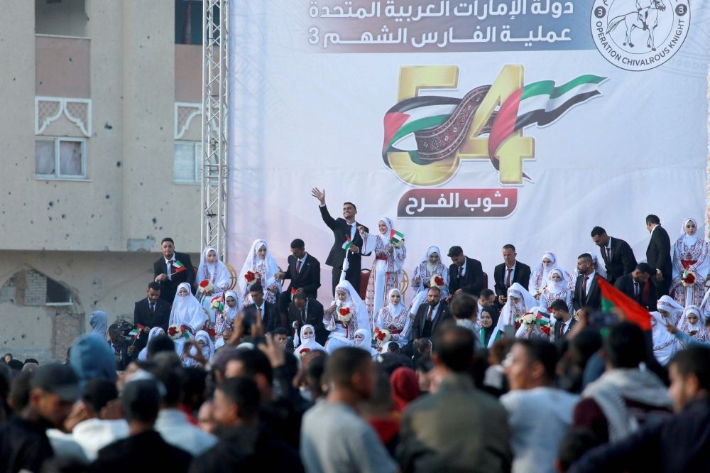 Some of the 54 brides and grooms gather on a stage during a mass wedding in Khan Yunis, southern Gaza Strip on December 2, 2025. ‘The Dress of Joy’, is a project helping 54 grooms in the the Gaza Strip to get married, an initiative that coincided with United Arab Emirates’ (UAE) 54th National Day. — AFP pic Some of the 54 brides and grooms gather on a stage during a mass wedding in Khan Yunis, southern Gaza Strip on December 2, 2025. ‘The Dress of Joy’, is a project helping 54 grooms in the the Gaza Strip to get married, an initiative that coincided with United Arab Emirates’ (UAE) 54th National Day. — AFP pic