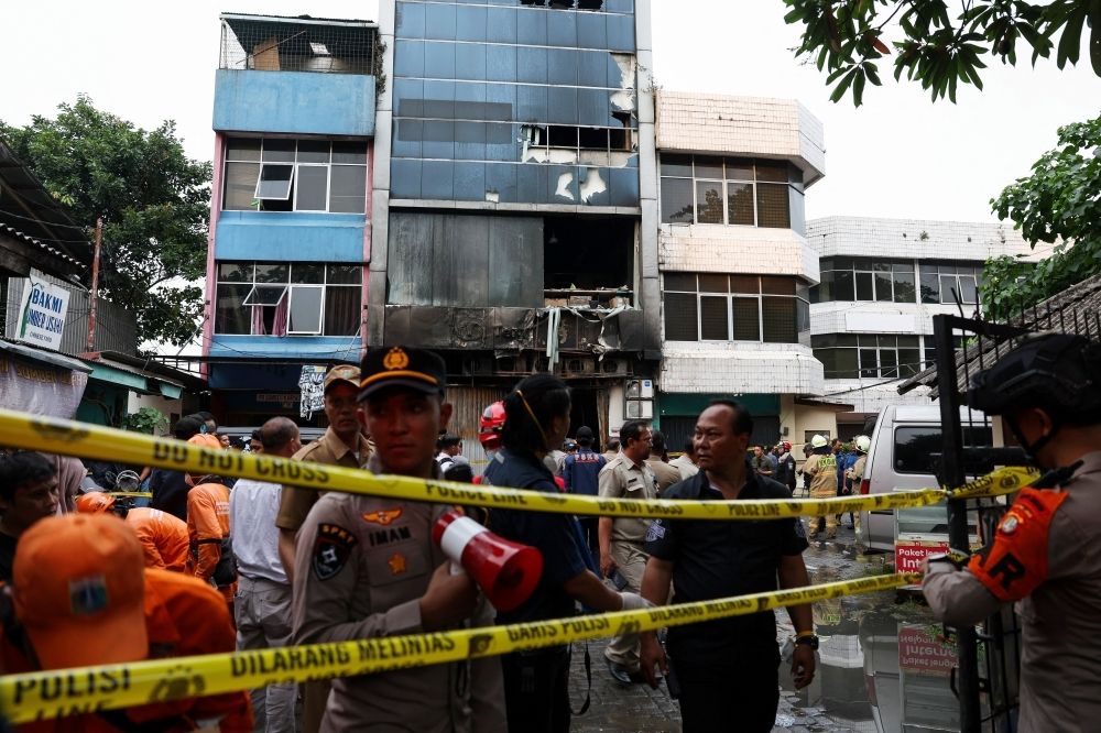 Battery explosion sparks Jakarta building blaze, 22 dead, mostly women Police officers stand near a seven-storey building damaged by fire, in Jakarta December 9, 2025. — Reuters pic