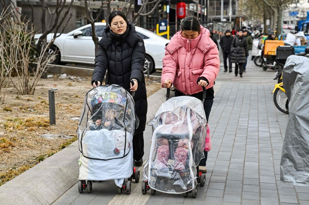 Women push baby strollers as they walk along a street in Beijing on January 4, 2026. — AFP pic Women push baby strollers as they walk along a street in Beijing on January 4, 2026. — AFP pic