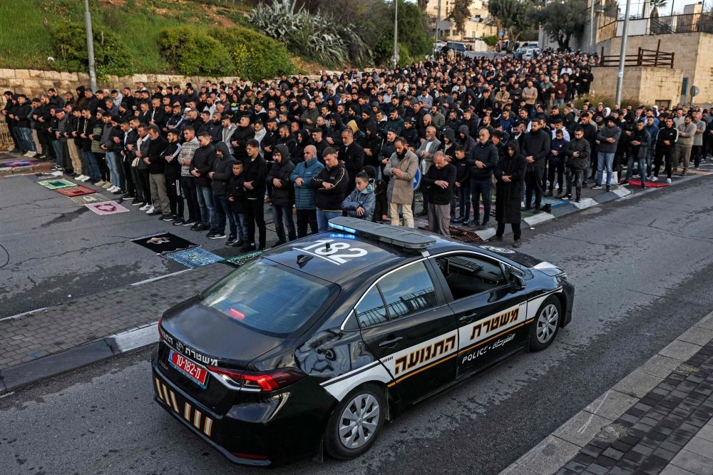 An Israeli police vehicle moves past Muslim worshippers gathering outside the Jerusalem old city walls on March 20, 2026 to attend attend the early morning prayers for Eid al-Fitr, marking the end of the holy month of Ramadan. — AFP pic An Israeli police vehicle moves past Muslim worshippers gathering outside the Jerusalem old city walls on March 20, 2026 to attend attend the early morning prayers for Eid al-Fitr, marking the end of the holy month of Ramadan. — AFP pic