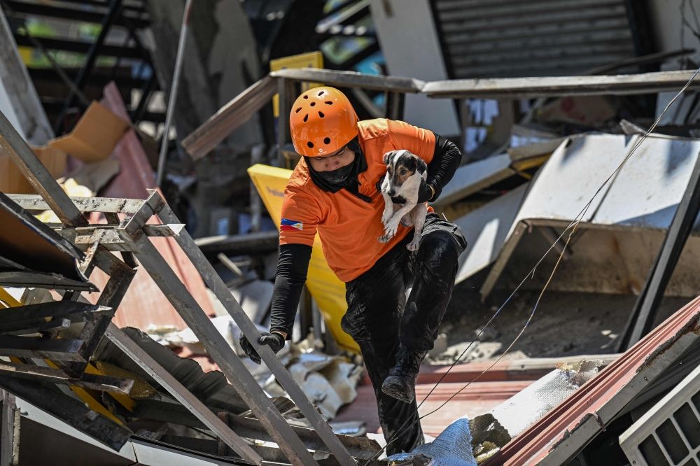 A responder carries a rescue dog while conducting search and rescue operations in a collapsed building after a 7.8 magnitude earthquake in General Santos City on June 9, 2026. — AFP pic A responder carries a rescue dog while conducting search and rescue operations in a collapsed building after a 7.8 magnitude earthquake in General Santos City on June 9, 2026. — AFP pic
