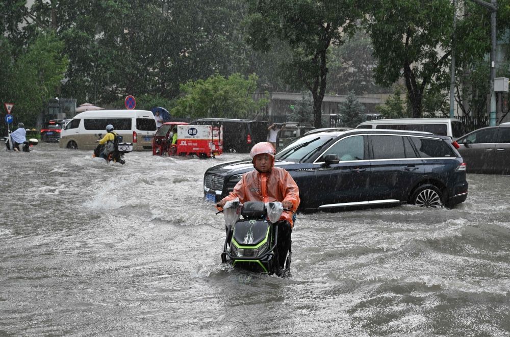 A man on a scooter makes his way along a flooded street in Beijing on July 7, 2026. — AFP pic A man on a scooter makes his way along a flooded street in Beijing on July 7, 2026. — AFP pic