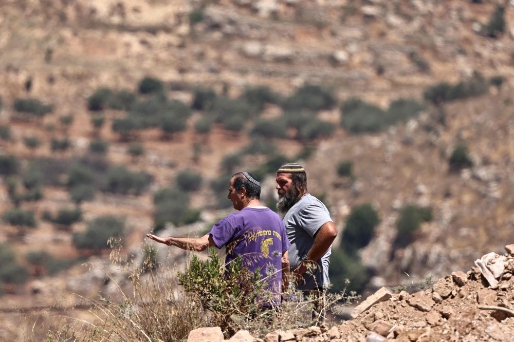 Israeli settlers stand near the al-Tireh neighbourhood at the western entrance of the city of Ramallah, in the occupied West Bank on July 14, 2026. — AFP pic Israeli settlers stand near the al-Tireh neighbourhood at the western entrance of the city of Ramallah, in the occupied West Bank on July 14, 2026. — AFP pic