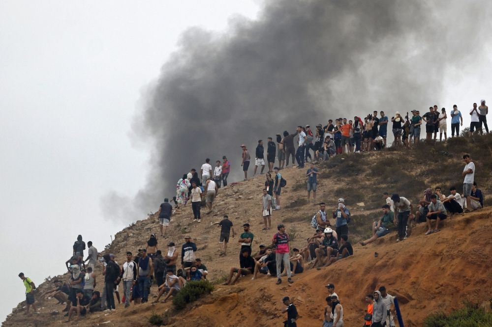 People gather on a hilltop as smoke billows from the site of clashes near Fnideq on the Morocco-Spain border on July 31, 2026. — AFP pic People gather on a hilltop as smoke billows from the site of clashes near Fnideq on the Morocco-Spain border on July 31, 2026. — AFP pic