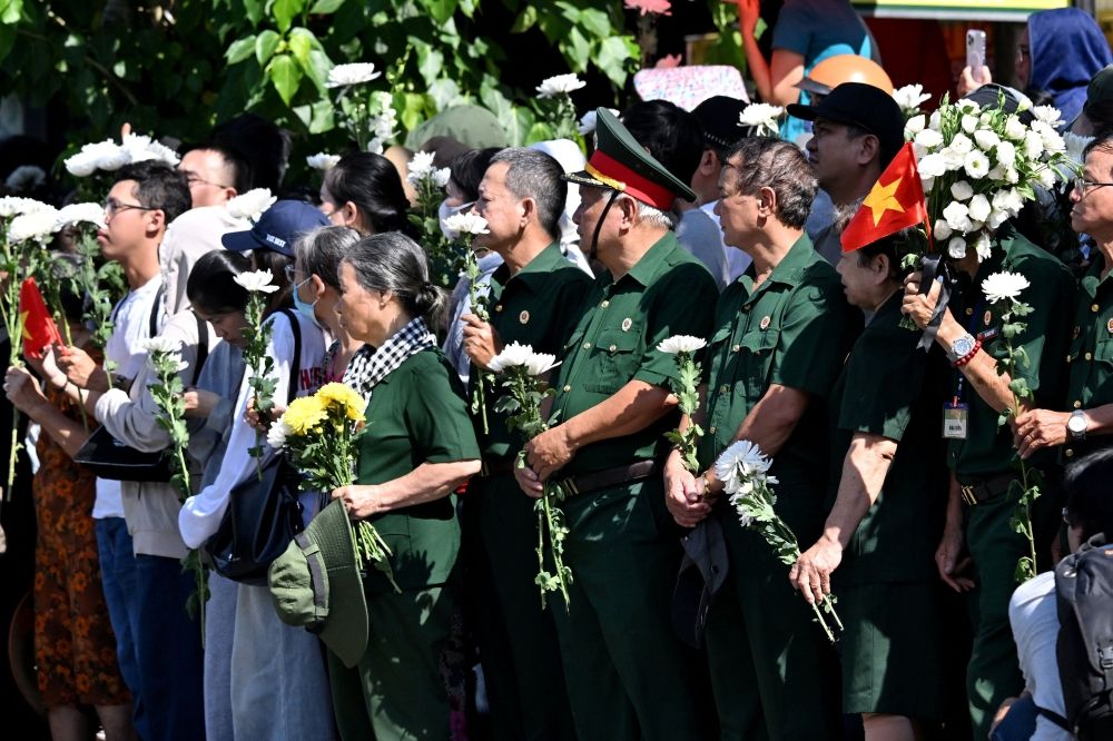 People gather with flowers by a roadside as they wait for the vehicle transporting the remains of fallen soldiers to pass by in Ho Chi Minh City October 14, 2026. — AFP pic People gather with flowers by a roadside as they wait for the vehicle transporting the remains of fallen soldiers to pass by in Ho Chi Minh City October 14, 2026. — AFP pic
