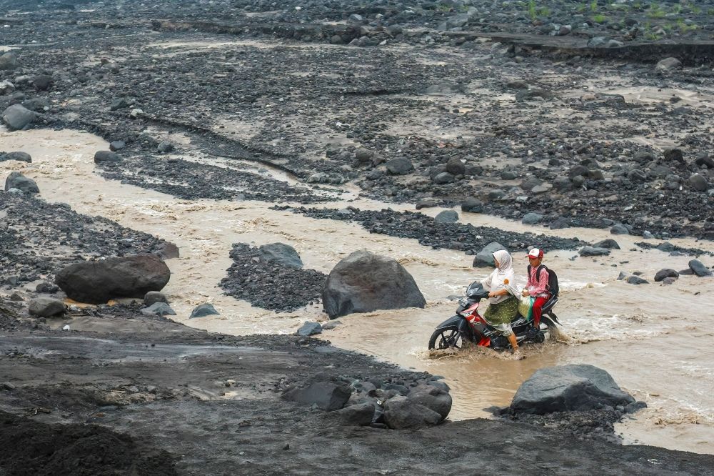 A woman rides a motorcycle with a student across a cold lava flood path from Mount Semeru following heavy rain at Jugosari village, Lumajang, East Java October 29, 2026. — AFP pic A woman rides a motorcycle with a student across a cold lava flood path from Mount Semeru following heavy rain at Jugosari village, Lumajang, East Java October 29, 2026. — AFP pic