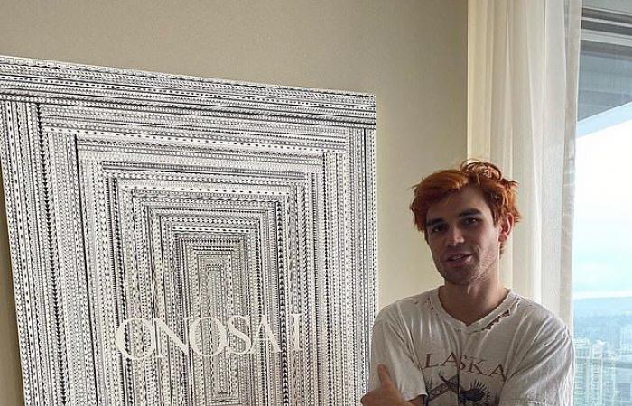KJ Apa looks thoughtful as he wears his guitar during a...