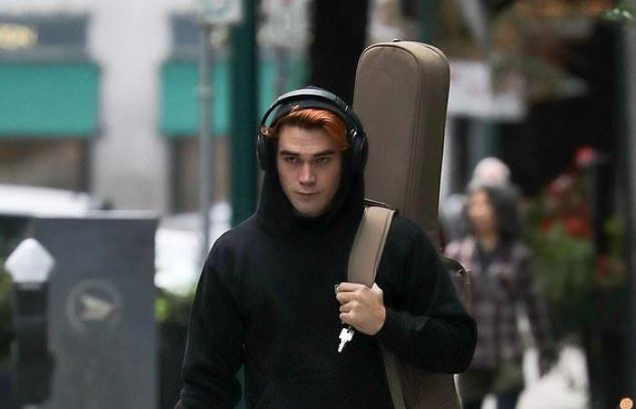 KJ Apa looks thoughtful as he wears his guitar during a...