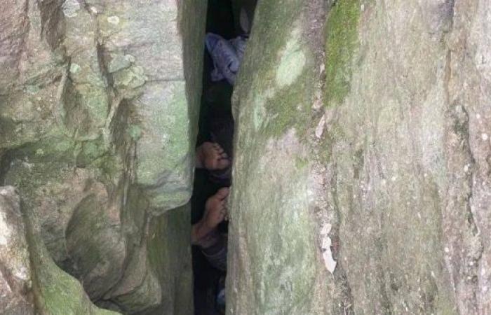 Woman reaching for phone gets stuck upside down in boulders